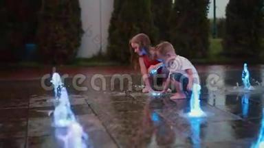哥哥和姐姐一起在彩色喷泉玩。 男孩和女孩在<strong>炎热</strong>的<strong>夏天</strong>接触喷水，弄湿了孩子们